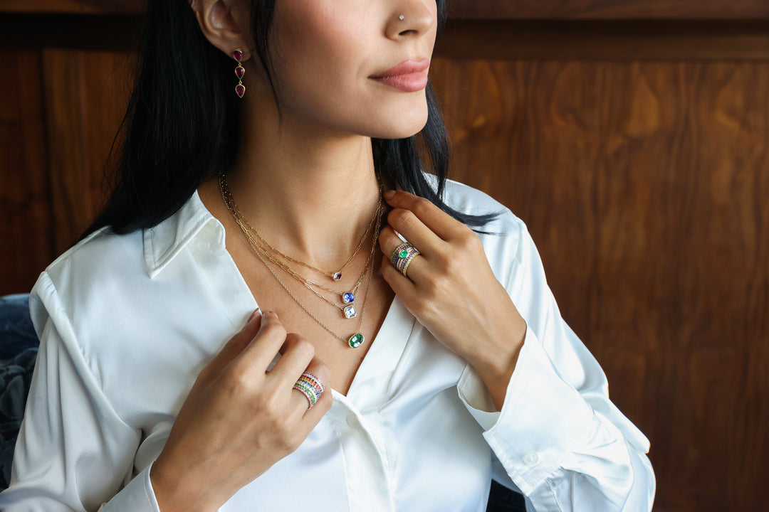 Closeup of woman wearing gemstone jewelry: gemstone rings, gemstone pendants, gemstone earrings, etc.