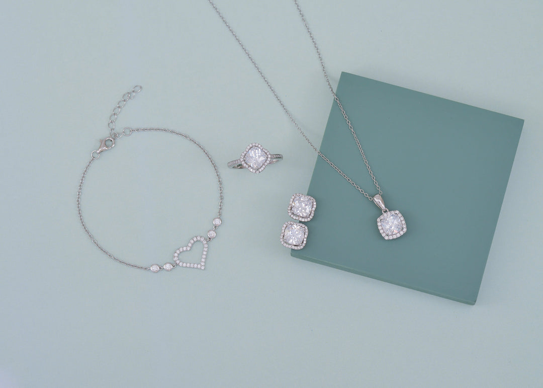 One large diamond ring in white gold, with a matching pair of diamond stud earrings, a diamond pendant necklace and a bracelet with a heart of diamonds on it 