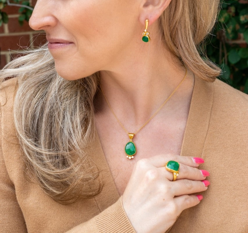 Blonde woman wearing emerald jewelry, ring, pendant necklace and earrings