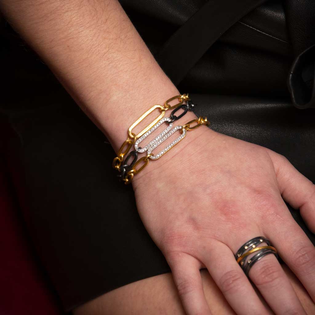 Close up of wrist wearing gold and diamond chain link bracelets